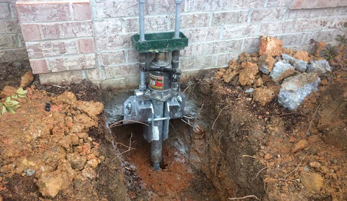 A heavy-duty 20-ton hydraulic bottle jack mounted onto a steel foundation pier