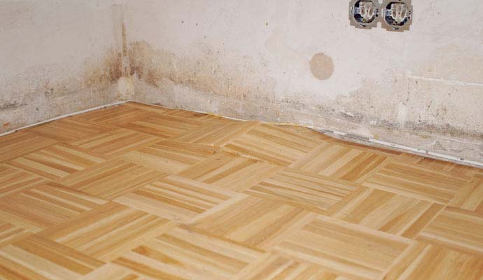 An interior view of a room with warped wood flooring