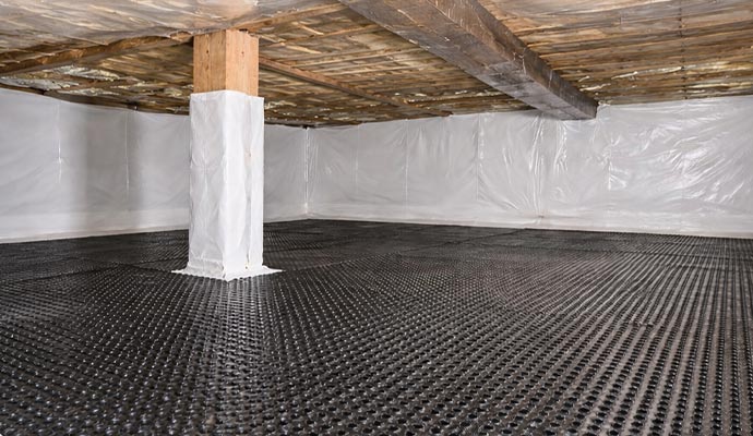 A professionally encapsulated crawl space with black drainage matting and white vapor barrier walls