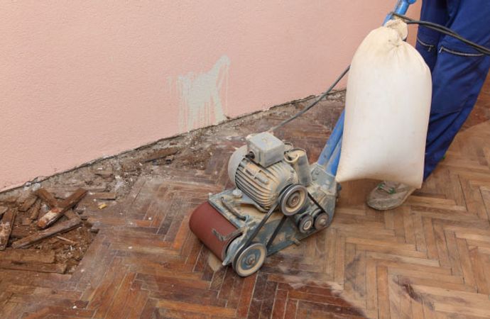 Expert repairing a damaged wooden floor using equipment