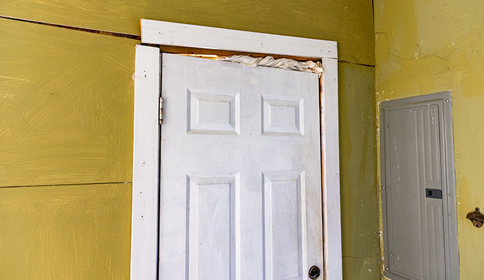 Door frame showing misalignment with visible gaps and exposed insulation