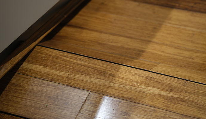 Close-up of a sloped wooden floor showing visible planks and noticeable gaps between them