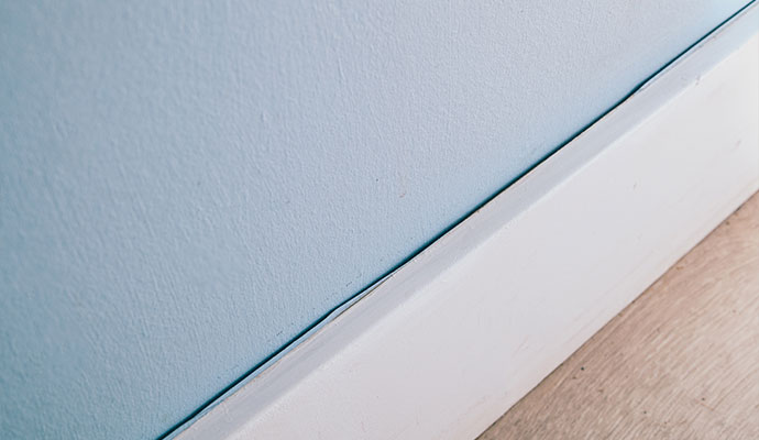 Gap forming between the wall and white baseboard trim