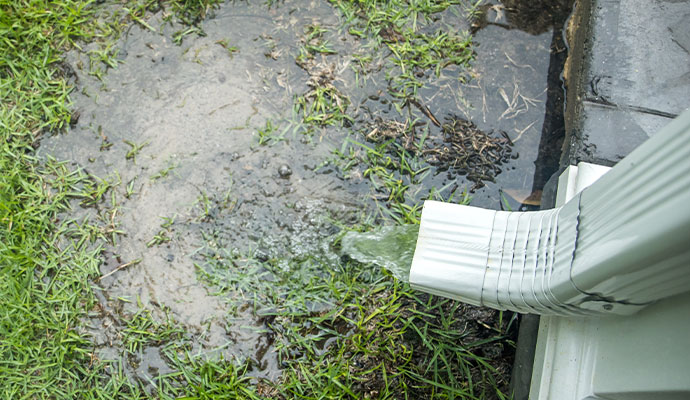 Gutter downspout dumping rainwater directly onto lawn
