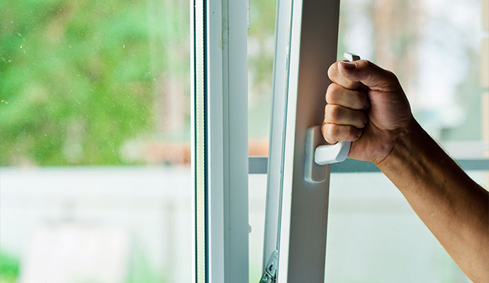 Hand opening a sticking white vinyl window