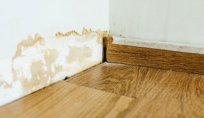 Uneven wood flooring and water damaged wall base